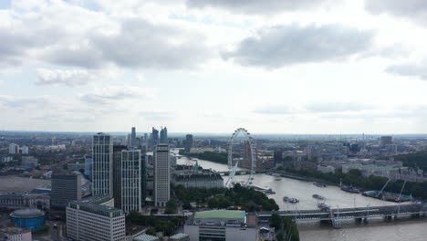 Panorama-curve-footage-of-buildings-along-River-Thames.-County-Hall-with-London-eye-and-Houses-of-Parliament-on-opposite-bank.-Modern-skyscrapers-in-background.-London,-UK