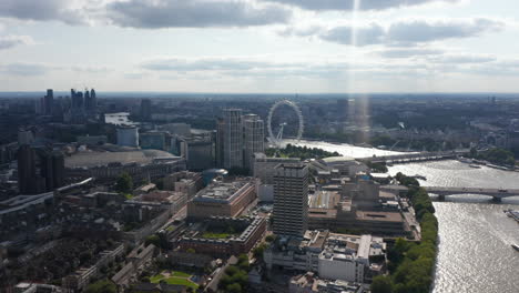 Aerial-panoramic-view-of-National-Theatre,-Royal-Festival-Hall-and-London-Eye-tourist-attraction-on-bank-of-glittering-River-Thames.-View-against-sunshine.-London,-UK