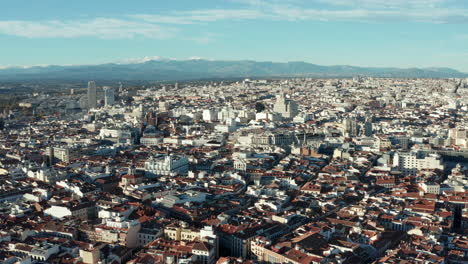 Ascending-footage-of-historic-city-centre-of-large-metropolis.-Aerial-panoramic-shot.-Mountain-range-in-distance.