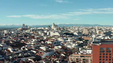 Ascending-panoramic-shot-of-buildings-in-city-centre.-Historic-buildings,-several-tower-above-other-development.-Mountain-ridge-in-distance.