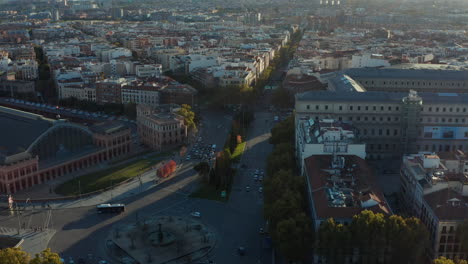 Descending-footage-of-crossroads-near-Atocha-train-station.-Tilt-up-reveal-of-buildings-in-urban-district.-Green-trees-lit-by-sun.
