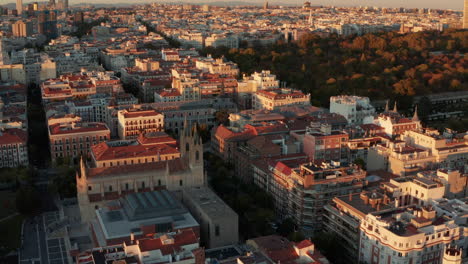 Aerial-ascending-footage-of-historic-buildings-in-town-illuminated-by-bright-sunset-light.-Old-church-and-large-palaces-near-El-Retiro-Park.