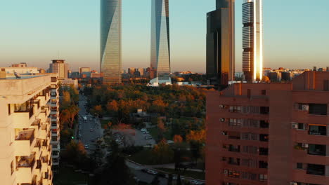Fly-around-apartment-houses-in-housing-estate.-Revealing-park-and-modern-high-rise-skyscrapers-in-Cuatro-Torres-Business-area-at-golden-hour.