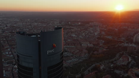 Aerial-view-of-top-of-tall-business-skyscraper--with-city-and-sunset-in-background.-Romantic-evening-footage.