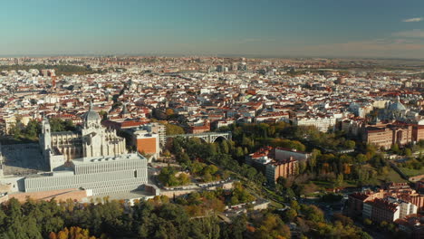 Forwards-fly-above-town-park.-Aerial-view-of-large-city-with-historic-landmarks.-Almudena-Cathedral-above-valley-spanned-by-Segovia-Viaduct.