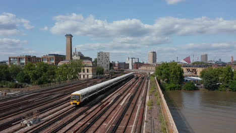 Forwards-fly-above-multi-track-railway-Grosvenor-Bridge-across-Thames-river.-Tracking-of-train-heading-to-Victoria-station.-London,-UK