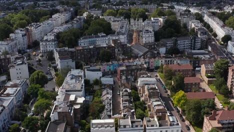 Slide-and-pan-shot-of-church-tower-among-town-houses-in-urban-neighbourhood.-Aerial-view-of-residential-district-in-city.-London,-UK
