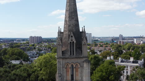 Pull-back-footage-of-church-spire.-Tower-of-gothic-building-in-park.-Elevated-view-of-urban-borough.-London,-UK