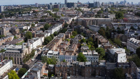Slide-and-pan-aerial-panoramic-footage-of-houses-in-urban-neighbourhood.-Tilt-up-revealing-cityscape.-London,-UK