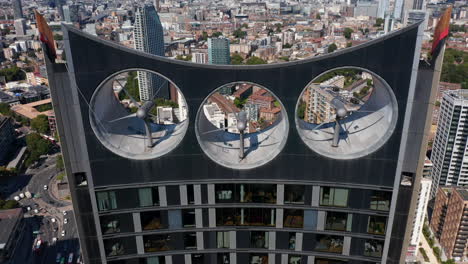 Ascending-footage-of-top-of-Strata-skyscraper-with-three-big-wind-turbines-for-producing-sustainable-energy.-Birds-eye-view-of-traffic-of-surrounding-roads.-London,-UK