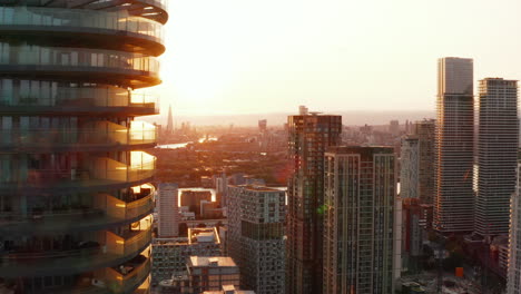 Forwards-fly-around-Arena-Tower-skyscraper-in-sunset-time.-Revealing-panoramic-evening-view-of-city.-London,-UK