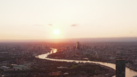 Aerial-panoramic-view-of-River-Thames-calmly-flowing-through-city.-Cityscape-against-setting-sun.-London,-UK