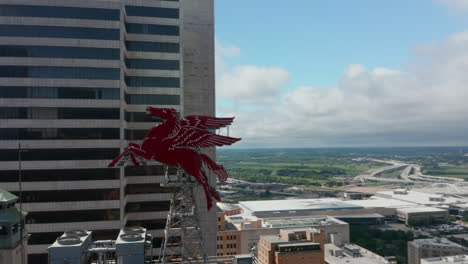 Drohnenluftbild-Von-Pegasus-Auf-Dem-Dach-Des-Magnoliengebäudes.-Fliegen-Um-Zwei-Massive-Rote-Skulpturen-Herum,-Die-Auf-Einem-Hohen-Gebäude-Thront.-Dallas,-Texas,-Uns