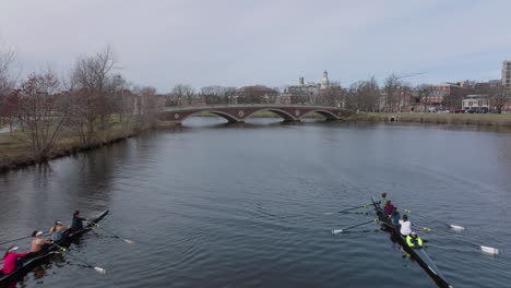 Fly-over-athletes-in-rowing-boats-on-calm-surface-of-Charles-river-near-John-W.-Weeks-Footbridge.-Boston,-USA