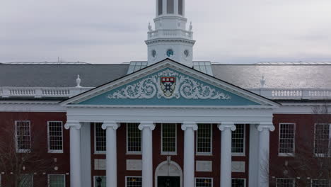 Pull-back-shot-of-Harvard-Business-School-coat-of-arms-in-decoration-above-main-entrance-to-Baker-Library.-Revealing-historic-building.-Boston,-USA