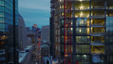 Aerial-ascending-footage-along-wall-of-new-modern-office-building-under-construction.-Downtown-at-twilight.-Boston,-USA