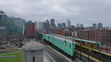 Forwards-fly-along-train-stop-in-city.-Subway-units-driving-on-overground-track-on-cloudy-day.-Boston,-USA