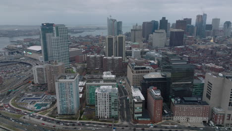 Aerial-static-shot-of-heavy-traffic-on-roads-in-city.-Hospital-and-modern-downtown-high-rise-buildings.-Boston,-USA