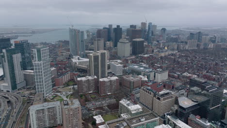 Aerial-panoramic-footage-of-city-centre-and-water-surface-in-background.-Cityscape-with-downtown-high-rise-office-buildings-on-cloudy-day.-Boston,-USA