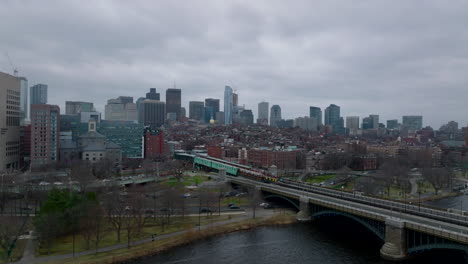 Slide-and-pan-footage-of-passenger-train-stopping-at-station.-Bridge-over-river-and-high-rise-buildings-in-background.-Boston,-USA