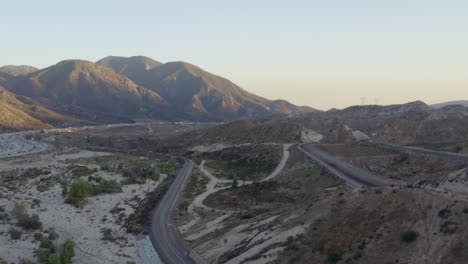 AERIAL:-Over-California-Countryside-with-Highway-and-Mountains-at-Sunset