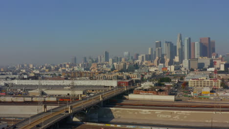 Antenne:-La-River,-Bahngleise-Mit-Der-Innenstadt-Von-Los-Angeles-Im-Hintergrund,-Sonnenlicht
