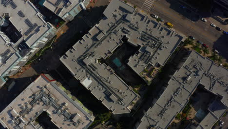 AERIAL:-Birds-Eye-View-over-Streets-of-Downtown-Los-Angeles,-california-with-cars,Traffic-and-rooftops,Pools,-Daylight