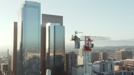 AERIAL:-Close-up-of-Construction-Site-Skyscraper-crane-in-Downtown-Los-Angeles,-California-Skyline-at-beautiful-blue-sky-and-sunny-sunny-flair-Day