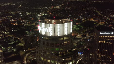Aerial-Establishing-Shot-of-Famous-US-Bank-Tower-Building-in-Los-Angeles-Skyline-at-Night,-Skyscraper-Wide-View-with-Cityscape-and-Mountains-in-background,-Circa-2019
