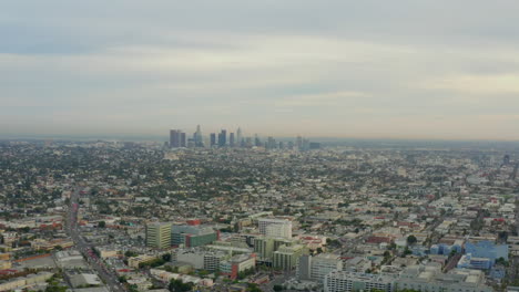 AERIAL:-Flight-over-Los-Angeles,-California-with-Skyline-in-background,-Cloudy-in-Daylight,