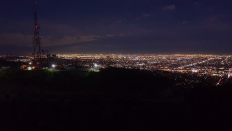 Luft-Hyper-Zeitraffer:-über-Dem-Hollywood-Schild-Bei-Nacht-In-Los-Angeles,-Kalifornien-Bei-Nacht-Mit-Leuchtendem-Stadtbild-Zeitraffer