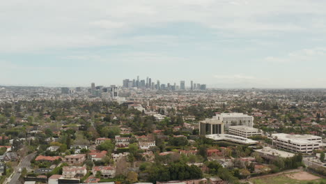 AERIAL:-View-over-Los-Angeles,-California-with-Downtown-in-Background-and-Beautiful-Rich-Green-Trees-and-Residential-Houses-on-Overcast-Day