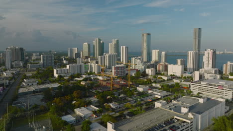 Aerial-ascending-footage-of-city-borough-illuminated-by-afternoon-sunshine.-High-rise-buildings-on-waterfront.-Miami,-USA
