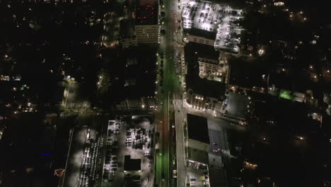 AERIAL:-Lookup-over-Wilshire-Boulevard-Street-in-Hollywood-Los-Angeles-at-Night-with-View-on-Downtown-and-Glowing-Streets-and-City-Car-Traffic-Lights