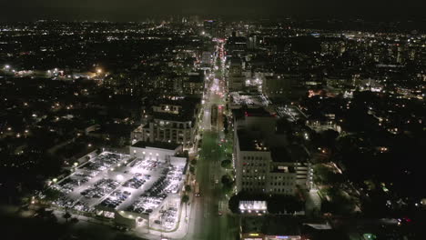 AERIAL:-Flight-over-Wilshire-Boulevard-Street-in-Hollywood-Los-Angeles-at-Night-with-View-on-Streets-and-City-Car-Traffic-Lights