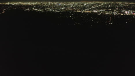 Langsame-Neigungsbewegung-über-Hollywood-Hügel-Bei-Nacht,-Die-Die-Lichter-Der-Stadt-Los-Angeles-Enthüllen