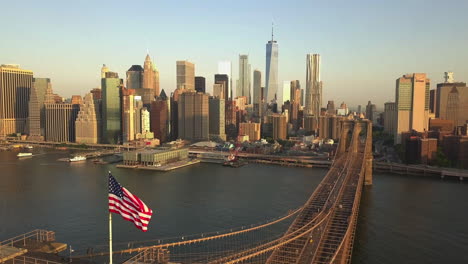 Antenne:-Rückwärtsflug-über-Die-Brooklyn-Bridge-Mit-Blick-Auf-Manhattan-Nahaufnahme-Der-Amerikanischen-Flagge-Bei-Sonnenaufgang,-Sonnenuntergang