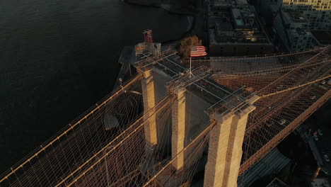 Amazing-aerial-view-of-Brooklyn-Bridge-in-sunset-time.-Suspension-tower-and-cables-lit-by-bright-sun.-Ascending-tilt-down-shot.-Brooklyn,-New-York-City,-USA