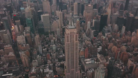 AERIAL:-Close-up-of-Empire-State-Building-with-Midtown-Manhattan,-Times-Square-in-the-background-at-Dawn,-Sunset