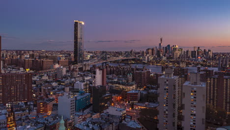 Aerial-hyperlapse-shot-of-city-at-twilight.-Gradually-dimming-sky-over-big-cable-stayed-bridge.-Manhattan,-New-York-City,-USA