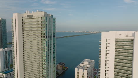 Forwards-fly-above-tall-apartment-buildings-on-waterfront.-Busy-road-and-bridge-leading-to-Miami-Beach.-Miami,-USA