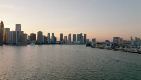Slide-and-pan-shot-of-high-rise-downtown-buildings-on-waterfront-against-colourful-twilight-sky.-Modern-city-borough-on-coast.-Miami,-USA