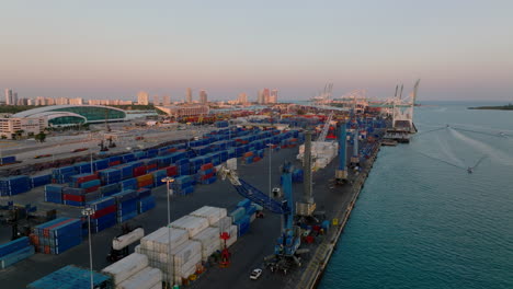 Aerial-descending-footage-of-machinery-and-stacked-naval-containers-in-harbour.-Transport-and-logistics-of-cargo.-Miami,-USA