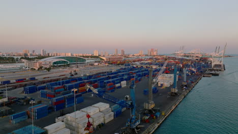 Rising-shot-of-containers-and-cranes-in-harbour-at-twilight.-Transport-and-logistics-of-cargo.-Miami,-USA