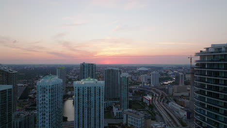 Backwards-fly-above-city.-High-rise-apartment-buildings-in-modern-urban-neighbourhood-at-dusk.-Miami,-USA