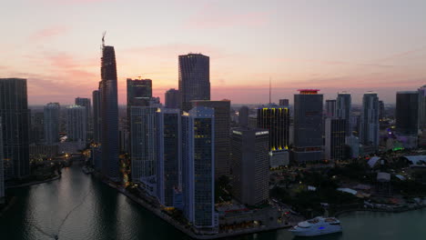 Breath-taking-evening-footage-of-tall-downtown-buildings-on-waterfront.-Pink-twilight-sky-in-background.-Miami,-USA