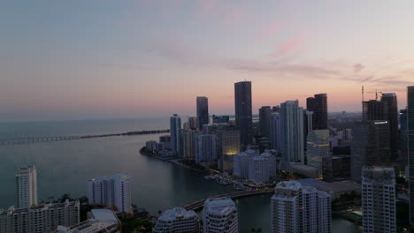 Forwards-fly-above-apartment-buildings-on-waterfront.-Group-of-tall-residential-houses-against-pink-twilight-sky.-Miami,-USA