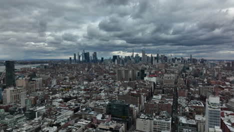 Forwards-fly-above-town-development.-Aerial-panoramic-view-of-downtown-skyscrapers-against-dramatic-cloudy-sky.-Manhattan,-New-York-City,-USA