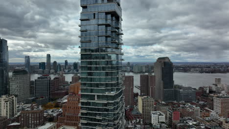 Rising-shot-of-high-rise-Jenga-Tower.-Futuristic-design-building-with-glass-facade-and-balconies.-Cloudy-sky.-Manhattan,-New-York-City,-USA