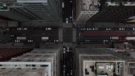Aerial-birds-eye-overhead-top-down-view-of-cars-passing-through-symmetrical-crossroad-between-high-rise-buildings-in-city.-Manhattan,-New-York-City,-USA